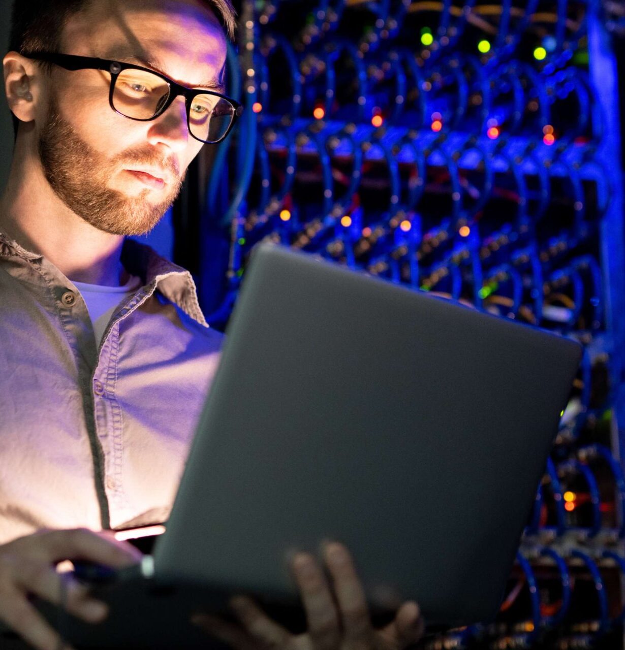 Man with a laptop and glasses in a server room